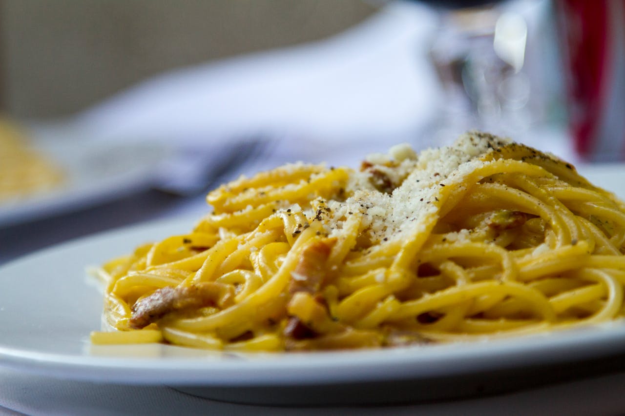 services-img Close-up of spaghetti carbonara topped with grated Parmesan cheese on a plate, perfect for Italian cuisine lovers.